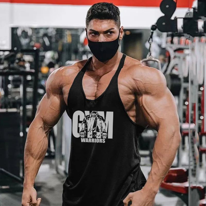 Man wearing Men’s Gym Tank Top Cotton Y-Back Fitness Muscle Bodybuilding Vest in gym, showcasing muscle and strength.