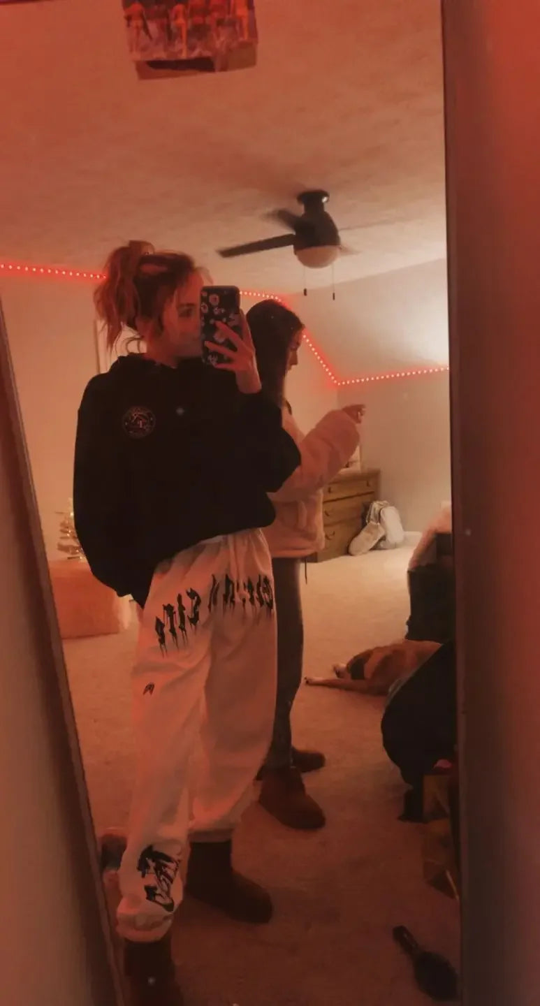 2024 Men’s Sports Pants Casual Gym Training Joggers for New Year worn by two people in a cozy indoor setting.